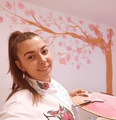 Meet the artist of Dede Art Artist of Dede art in front of a mural